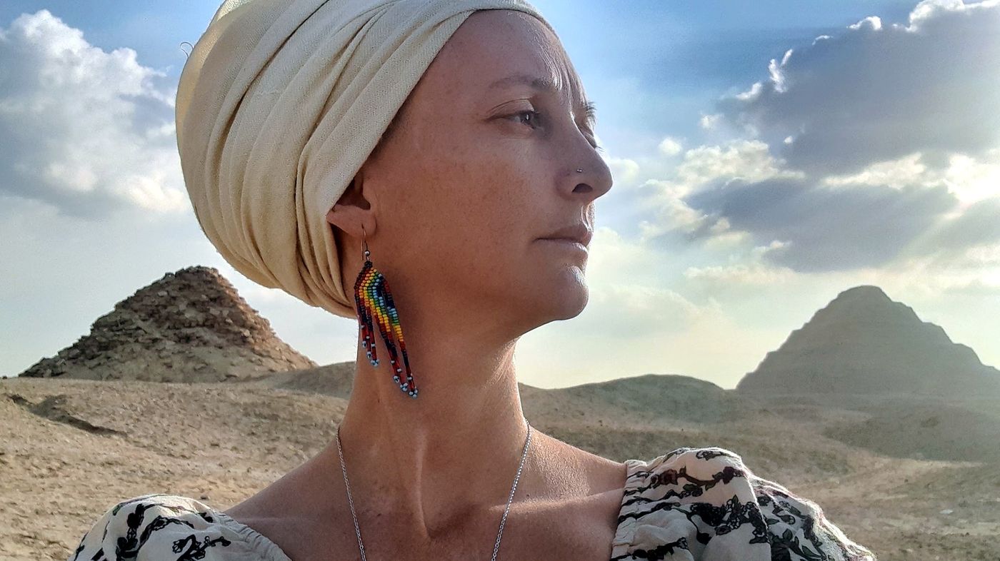 Maya Nassi in the desert, with pyramids behind her